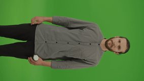 Vertical Video.Portrait of a Distressed Young Bearded Man with a Cough and Sneeze and His Hand Covering His Face,He Taking Some Pills to Get Well on Green Screen, Chroma Key.Seasonal Disease Concept