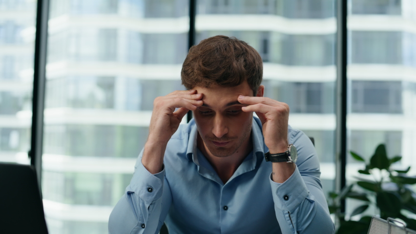 Stressed unmotivated man manager confused by mistake in documents looking papers using laptop at office desk close up. Depressed businessman suffering from headache disappointing by work in company. | Shutterstock HD Video #1095837867