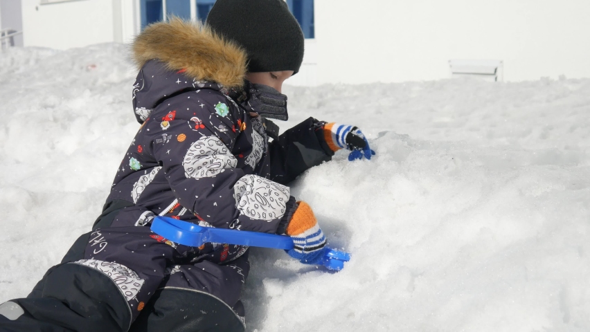 Close-up of a happy boy having a fun digging the snow outdoors