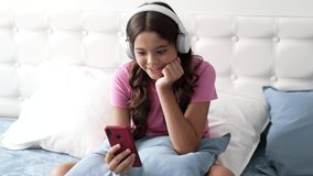 cheerful little girl watching webinar in headphones in bedroom, childhood - Powered by Shutterstock - Get 15% off with code: PIKWIZARD15