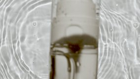 Bottle for serum, micellar toner and emulsion falling down in water and splashes on white background. Slow motion. Medical skin care. Video of packaging for design, advertising of a cosmetic product.
