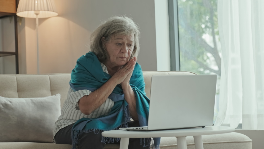 Elderly woman sitting on sofa at home and speaking via online video call on laptop | Shutterstock HD Video #1095846845