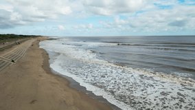Drone video footage of Seaside Waves Near A Sandy Beach Shore On A Beautiful Sunny Summer Day