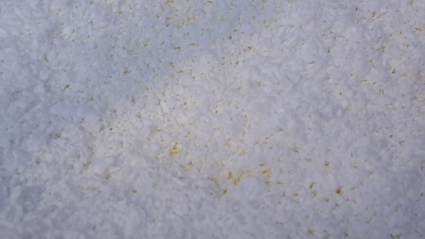 Human hand with white polystyrene beads on yellow background with space for text.