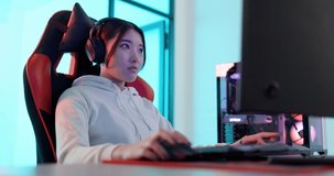 Video game, streaming and gamer woman with futuristic gaming room or office with computer, keyboard and mouse. Gen z, cyber and geek asian girl with headphones, focus in competition esports pc game