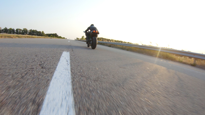Follow to biker riding on modern sport motorbike at highway during sunny autumn day. Motorcyclist racing his motorcycle on country road. Guy drive bike during trip. Concept of journey. Aerial shot | Shutterstock HD Video #1095862531