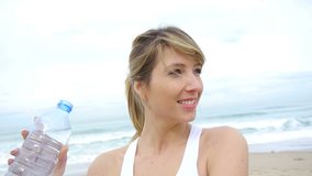 Portrait of woman drinking water from bottle at the beach
