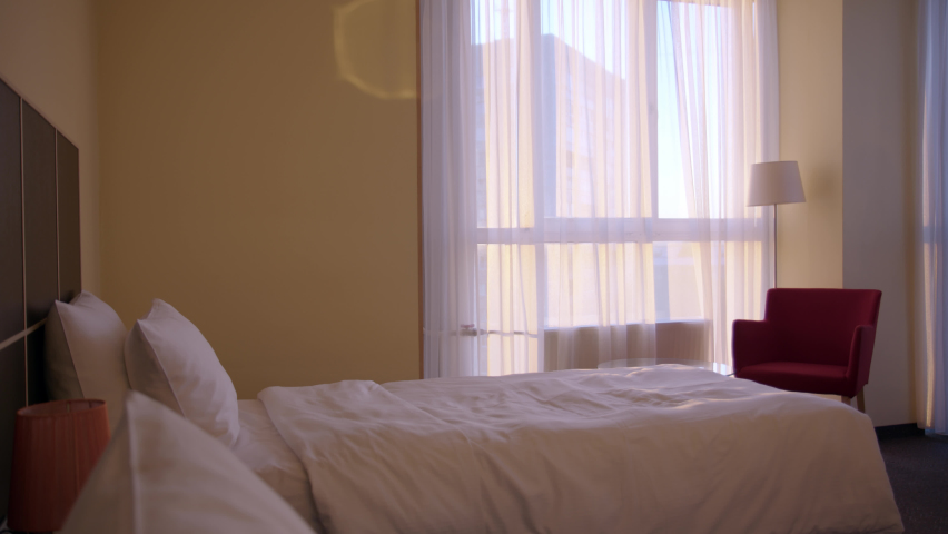 happy young woman checked into hotel and came to her room, happy jump on bed. Traveler on vacation, concept of beautiful vacation in hotel, girl is glad to arrive at point of rest and relaxation.
