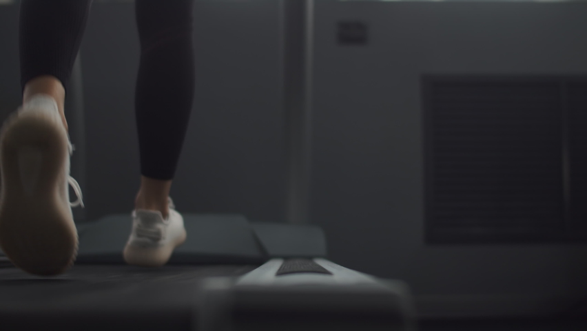 Close up sports shoes woman muscular legs feet during running on treadmill workout at indoor fitness gym, Jogging shoes for walking on a treadmill she exercises on cardio | Shutterstock HD Video #1095882183