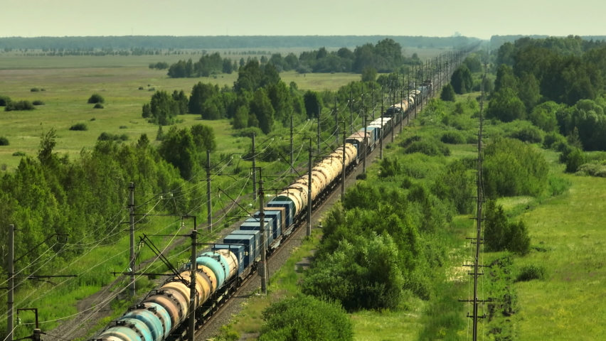 Freight long train carries with oil tank and petrol carriages an electric locomotive by Trans Siberian two-sided railways in plain land, steppe. Aerial drone wide view at summer sunny day Royalty-Free Stock Footage #1095882549