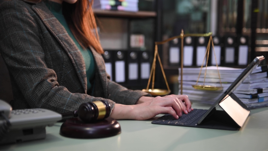 justice and law concept. asian woman lawyer working and judge in a courtroom the gavel, working with tablet and laptop and digital tablet computer on table  Royalty-Free Stock Footage #1095889591
