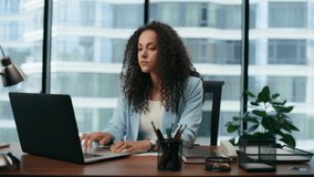 Confident business lady having online meeting with clients sitting office desk closeup. Portrait of successful latin woman manager concluding contract by video call. Curly businesswoman working remote