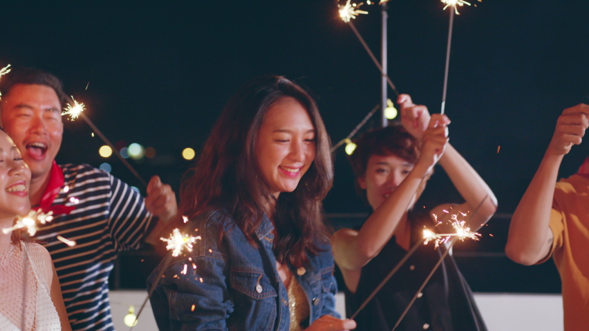 Group of happy young Asian people with friends celebrating party on rooftop holding sparklers fireworks and enjoy together at night - Powered by Shutterstock - Get 15% off with code: PIKWIZARD15