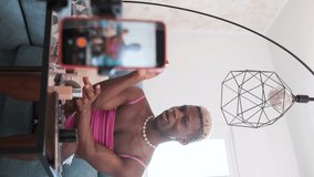 Transgender beauty content creator applying makeup to mobile phone camera. Vertical orientation