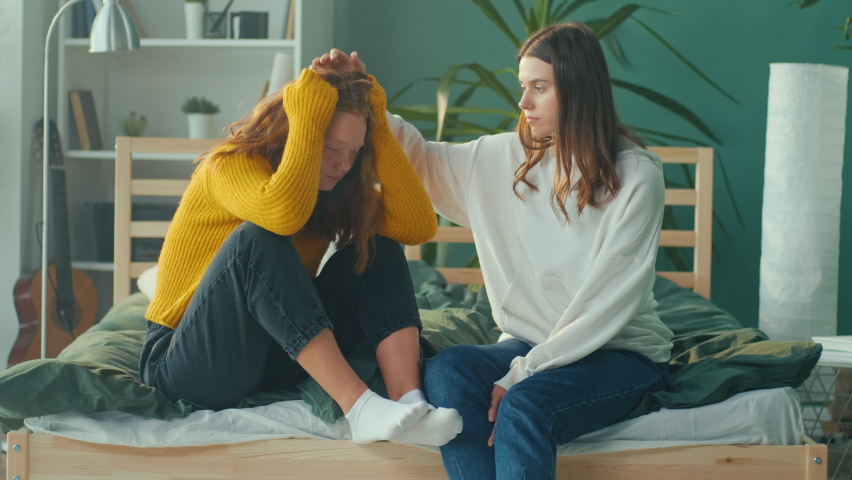 Stressed Red Haired Teenage Girl Emotionally Crying on Couch While Friend Sitting near and Trying to Calm her Down. Friendly Support. Teenage Psychological Trauma, Adolescence Concept. Mental Health. Royalty-Free Stock Footage #1095906137