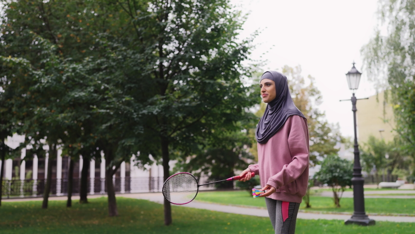 Athletic middle-eastern woman playing badminton in park, training time, hobby