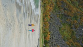Two young caucasian woman walking on a beach on Senja island, Norway - Vertical Video