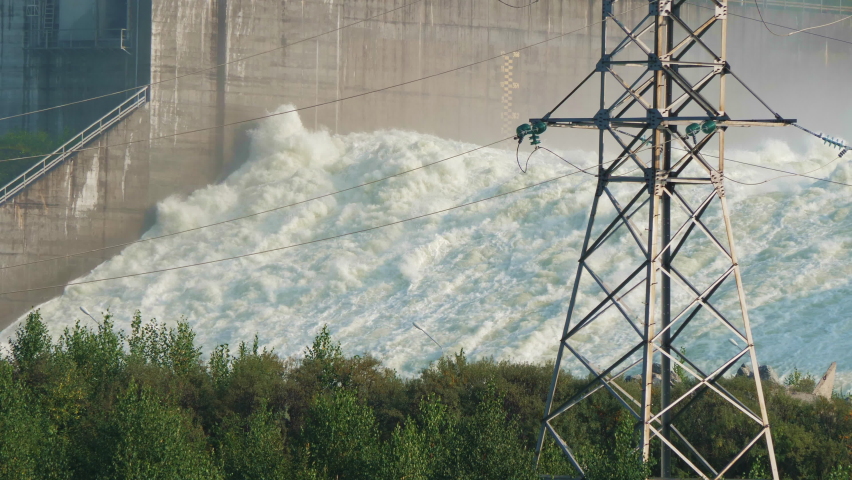 Spillway of hydroelectric power station near forest, electrical transmission line. Hydropower plant throws out surplus water. Ecological industrial disaster, environmental man-made accident Royalty-Free Stock Footage #1095919269