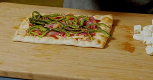 Placing ingredients on flatbread to make a flatbread pizza dish.