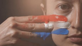 Supporter Painting Face and Looking at Camera. Football Fan Preparing for the Match. Colored Face with Flag Colors Red, White and Blue. Slow Motion 4K Prores 422 - Powered by Shutterstock - Get 15% off with code: PIKWIZARD15