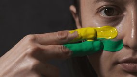 Supporter Painting Face and Looking at Camera. Football Fan Preparing for the Match. Colored Face with Flag Colors Yellow and Green. Slow Motion 4K Prores 422 - Powered by Shutterstock - Get 15% off with code: PIKWIZARD15