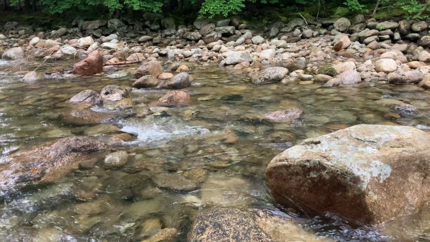 New Hampshire’s Pemigewasset River with crystal clear water streaming through the woods and lots of rocks along the river’s path.  Located in the White Mountains.