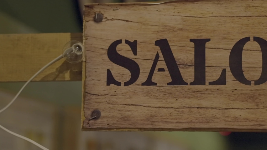 This panning video shows a rustic, wooden "saloon" sign.