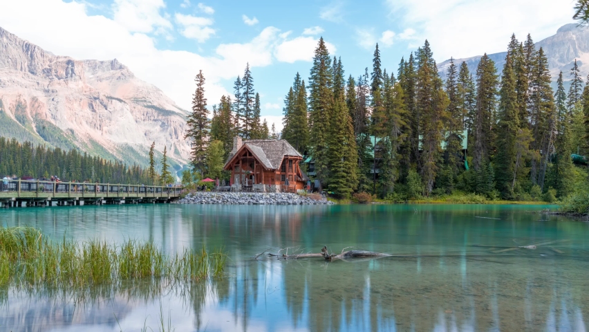 4K time-lapse UHD video of scenery of wooden house with rocky mountains and cloudy blowing reflection on Emerald Lake,a Glacial Lake at Yoho national park in the mountain parks of the Canadian Rocky