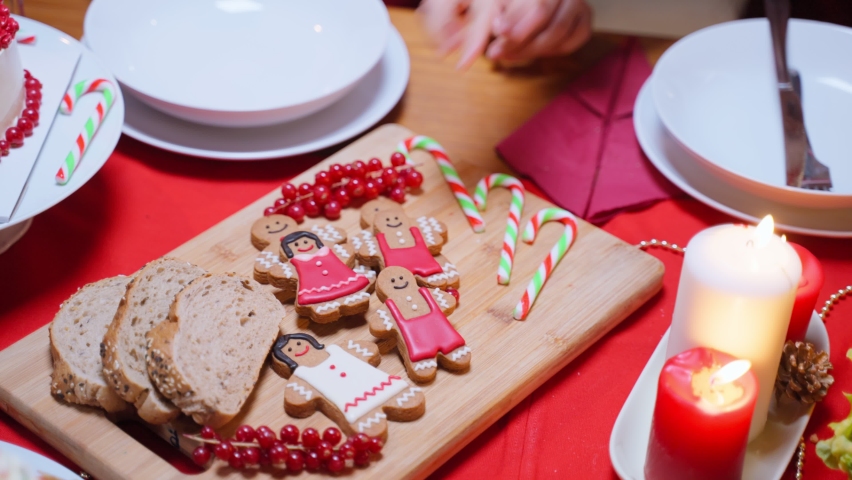 Close up hands of people taking a cookies biscuits from wooden board. Attractive diverse family having dinner eating sweet foods to celebrate holiday Thanksgiving, X-mas eve on dining table at home.