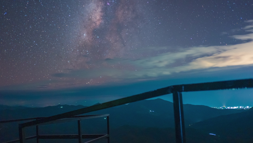 Beautiful Time-lapse of The Milky Way over the mountains with a balcony fence in the foreground at "Wa Grue Jo viewpoint" in Mae Hong Son province Northern Thailand.