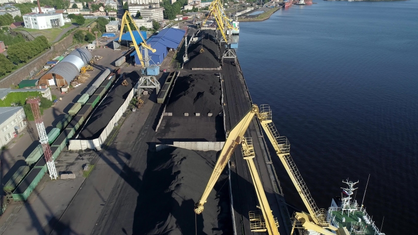 Aerial view of a coal transshipment in the port terminal. View of port cranes and piles of coal.