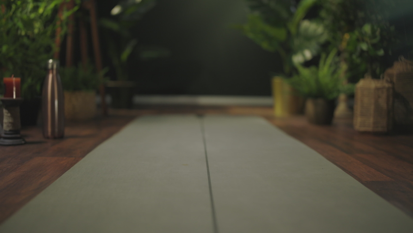 Closeup on middle aged woman with yoga mat folding mat in the green living room.