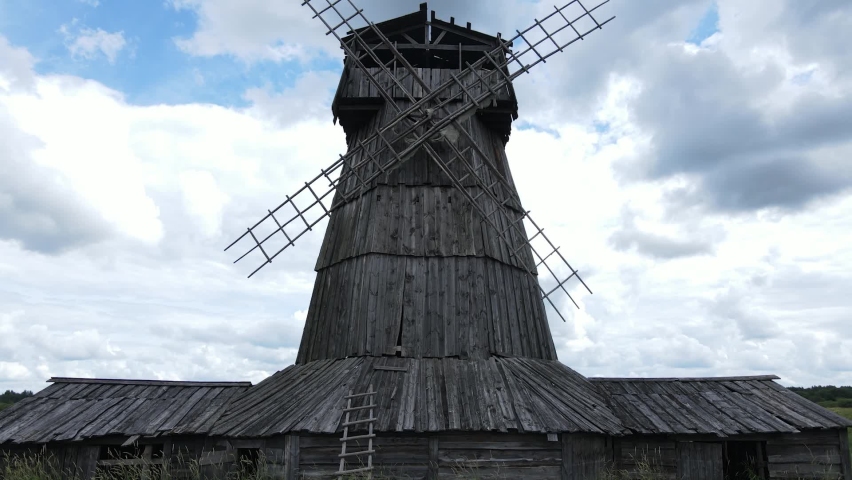 aerial view an old wooden mill stands on an island in a green field by the river in summer