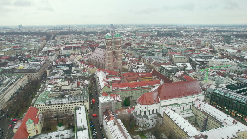 Munich, Germany: Aerial view of capital city of Bavaria in winter, famous cathedral Frauenkirche (Cathedral of Our Lady), fragments of snow on roofs - landscape panorama of Europe from above Royalty-Free Stock Footage #1095958165