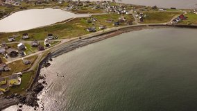 Aerial Newfoundland cinematic shot over beaches and colourful homes dotted across peninsulas and rocky Atlantic shores in Bonavista.