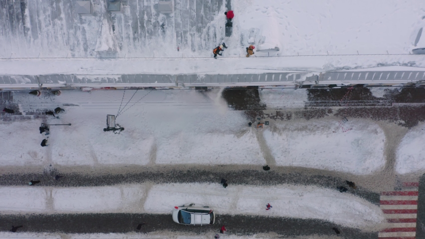 Aerial top view workers removing snow from the roof. Squad of janitors sweeping snow. Royalty-Free Stock Footage #1095963291