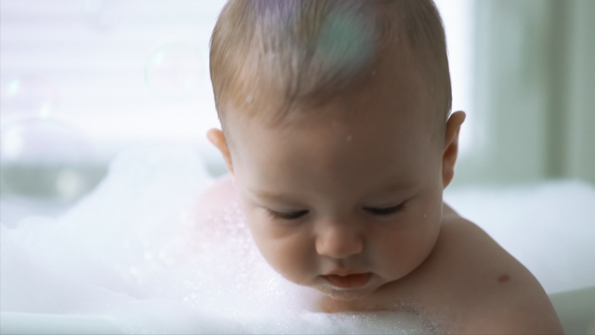 Cute healthy six month old baby bathing with foam and soap bubbles Royalty-Free Stock Footage #1095963469