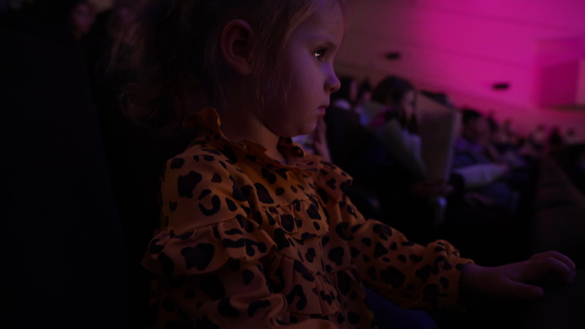 Little girl in the theater watch the performance. Toddler in the auditorium looking at the stage. Royalty-Free Stock Footage #1095970135