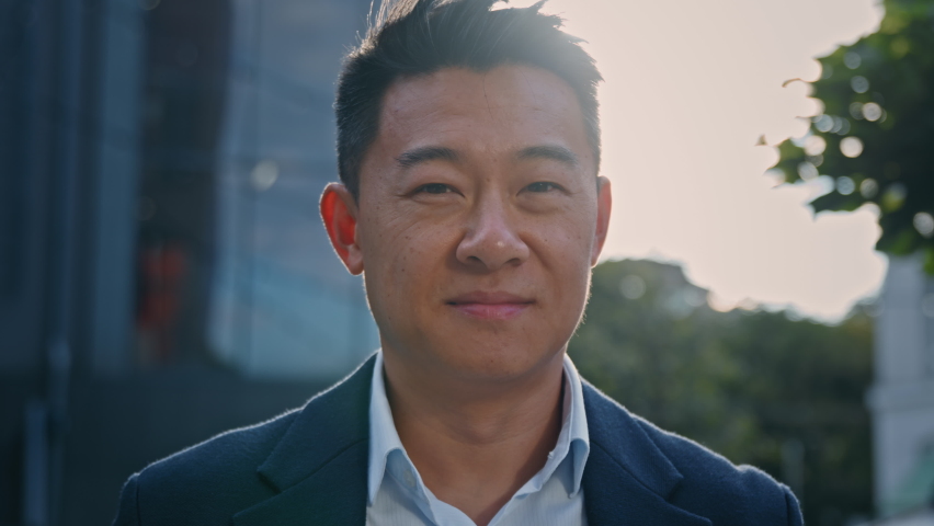 Outdoors portrait Asian 40s mature businessman smiling happy in city in sun lights. Close up glad success cheerful positive middle-aged man business CEO manager entrepreneur employer sunbeams sunset | Shutterstock HD Video #1095971541