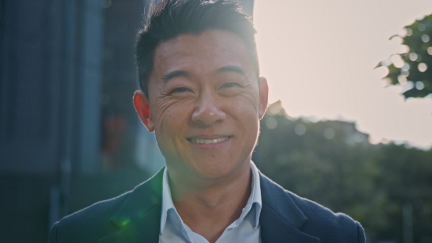 Outdoors portrait Asian 40s mature businessman smiling happy in city in sun lights. Close up glad success cheerful positive middle-aged man business CEO manager entrepreneur employer sunbeams sunset | Shutterstock HD Video #1095971541