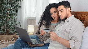 Married couple husband and wife man and woman consumers clients in bedroom shopping buying goods in internet store delivery service booking with laptop online e-commerce ordering with bank credit card - Powered by Shutterstock - Get 15% off with code: PIKWIZARD15
