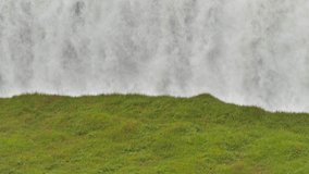 loop of water jet falling down from the waterfall,grass field in the foreground,background loopable footage