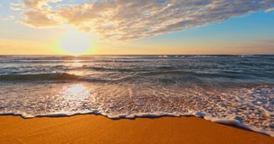 Golden ocean beach sunrise and splashing waves on the sea sand, 4K video of nature landscape, ocean tropical seascape. Low angle view