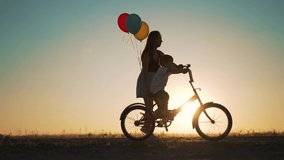 Happy family in park at sunset. kid learns to ride bike in park on green grass. Happy kid on his birthday. Mom helps teach her son to ride bike at sunset in park. Mom helps child. Kid on bike in park - Powered by Shutterstock - Get 15% off with code: PIKWIZARD15