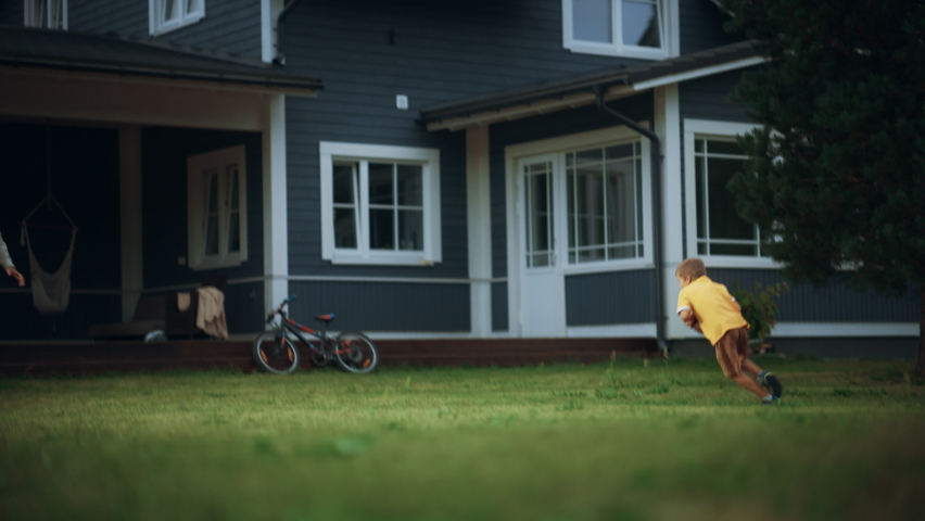 Young Athletic Father Playing Ball with His Young Son. Dad Teaching the Boy to Play American Football. Kid Learning to Throw the Rugby Ball Correctly. Family Members Playing Outside Their Home.