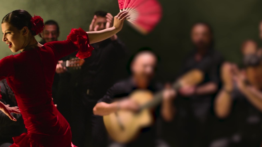 Beautiful stylish female artist dancing spanish style dance . Group of men playing on guitar and applauds to the dancer woman . Concept footage of spanish traditional culture . Waving cloth of skirt 