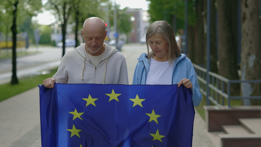 Mature couple holding a european union flag looking and smiling at camera. People, political and relationship concept Royalty-Free Stock Footage #1095988365