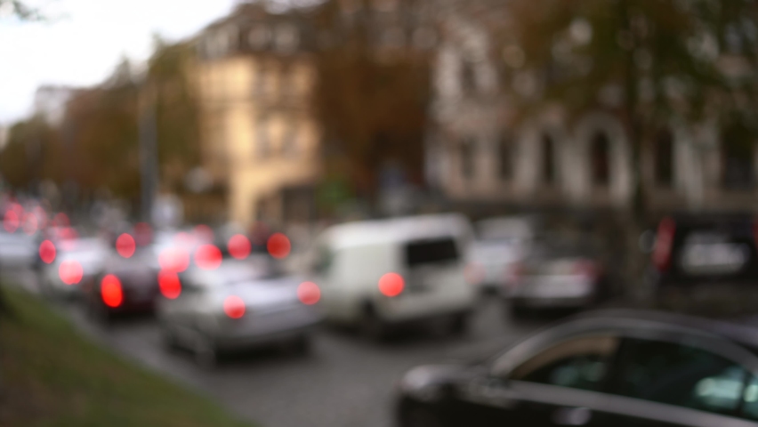 Cars In Traffic. Car traffic in a city street road. Defocused footage of parked and moving cars on background at dusk. Dense city traffic, cars are moving slowly, traffic jam.