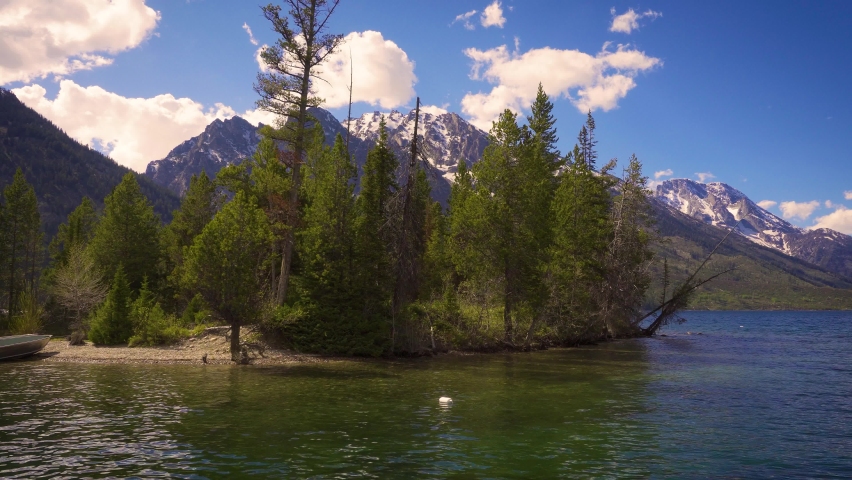 Boat ride on the Jenny Lake in Grand Teton National Park, Wyoming, USA, with forests and snowy mountains seen on the side. 4K UHD video.