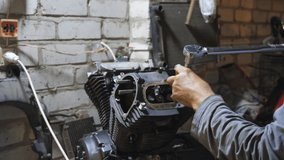 Adult mechanic repairing motor of motorcycle at garage. Professional repairer screwing bolt using tool at workplace. Male repairman working at workshop. Concept of maintenance service. Dolly shot - Powered by Shutterstock - Get 15% off with code: PIKWIZARD15